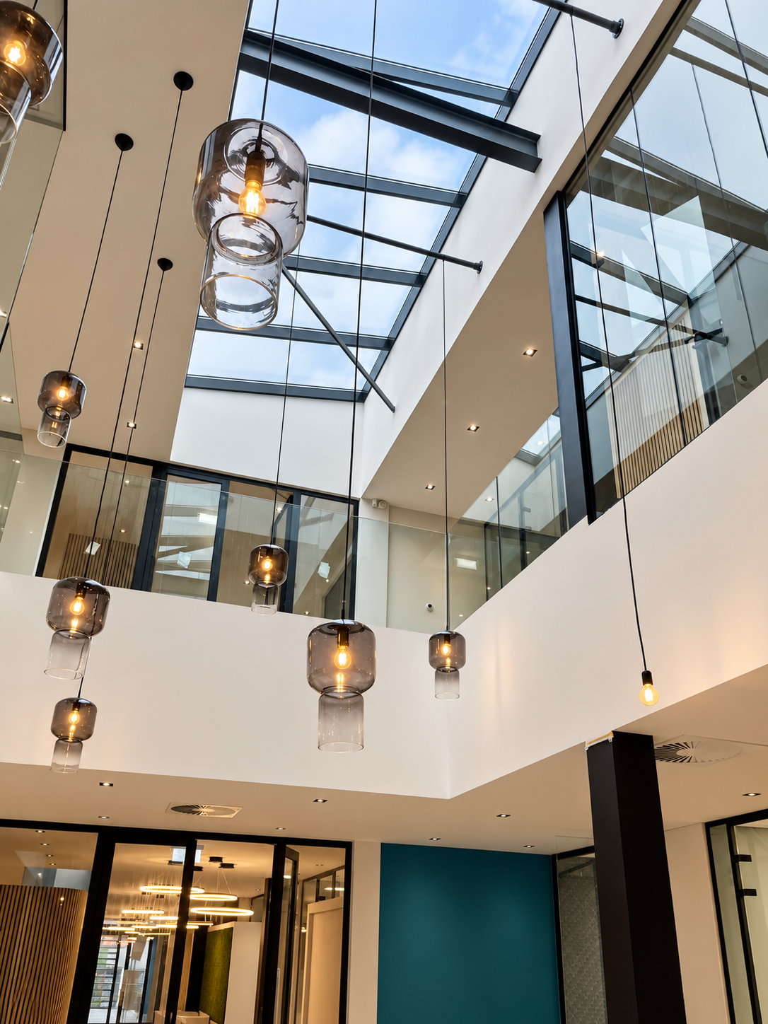 Modern atrium met glazen hanglampen en strakke lijnen